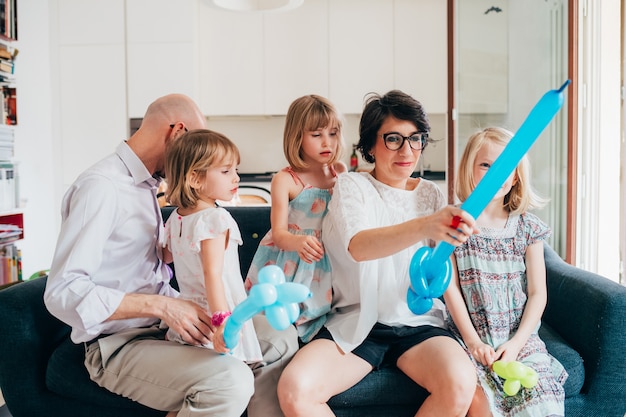 Family indoor sitting couch playing with balloon toys