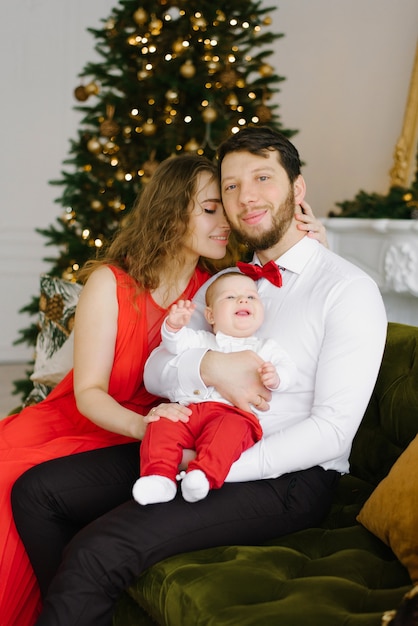 The family is enjoying in the holidays.They are celebrating their first Christmas together. Happy family in the room with the Christmas tree.