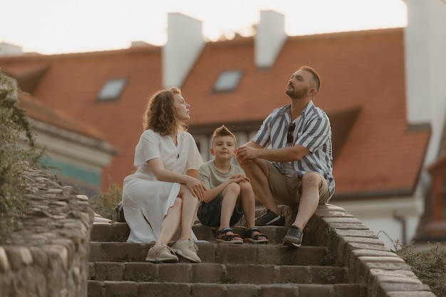 A family is relaxing on the stairs between roofs in an old European town