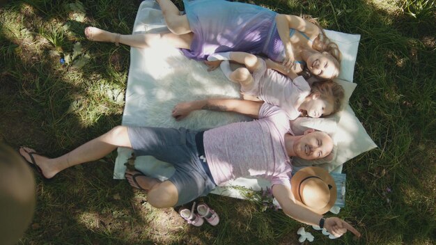 Family is resting in park - father, mother and daughter have breakfast - top view, close up