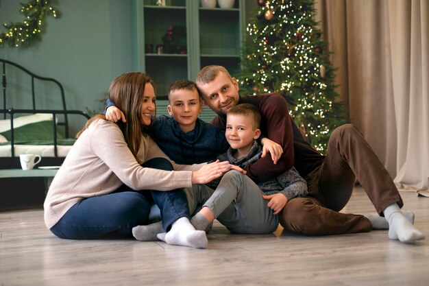 A family is sitting in apartment near Christmas tree