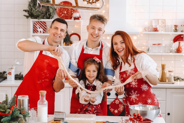 The family is standing in the kitchen and holding the dough in their hands before Christmas
