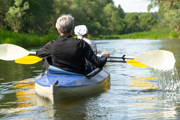 領主とセニョーラの家族カヤック旅行 川でボートを漕ぐ老夫婦 水上ハイキング 夏の冒険 年齢関連のスポーツ 精神的若さと健康 観光 活動的な老年