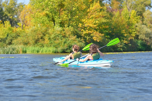 Famiglia kayak, madre e figlia pagaiare in kayak nel tour in canoa sul fiume divertendosi, weekend autunnale attivo e vacanze con bambini, fitness