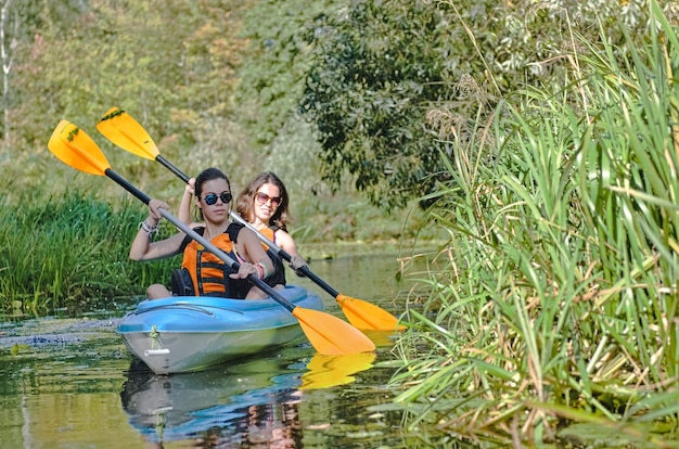 Family kayaking mother and daughter paddling in kayak on river canoe tour having fun