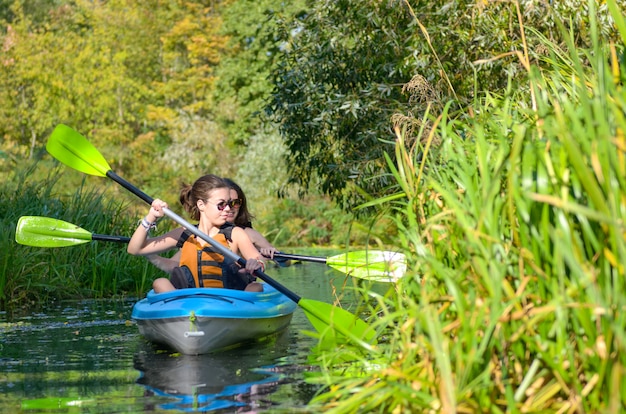 Famiglia kayak, madre e figlia pagaiando in kayak durante il tour in canoa sul fiume divertendosi