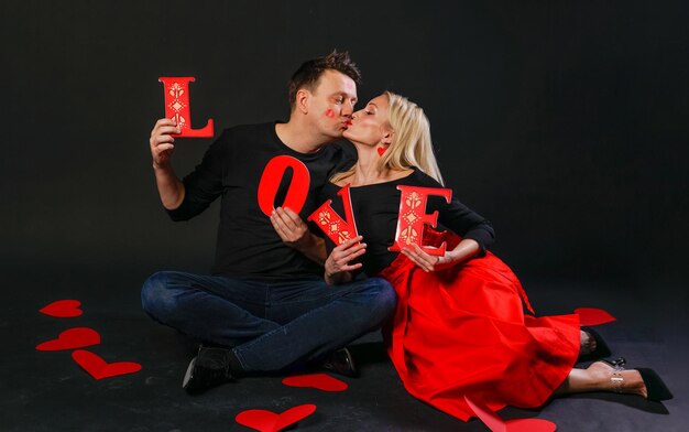 Foto la famiglia mantiene la parola amore amore san valentino sfondo flirt board sul layout dei cuori del pavimento