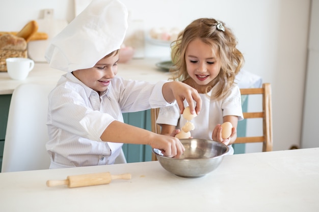 Family kids in white chef uniform preparing food on the kitchen