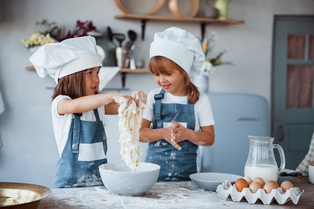 Family kids in white chef uniform preparing food on the kitchen.