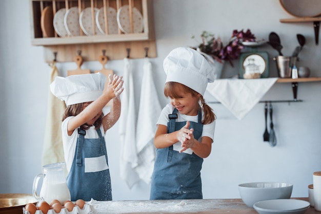 Family kids in white chef uniform preparing food on the kitchen.