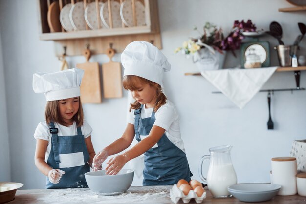 부엌에서 음식을 준비하는 흰색 요리사 유니폼을 입은 가족 아이들.