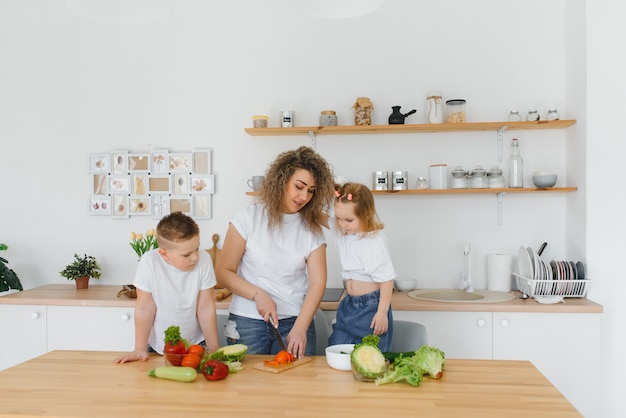 Family in a kitchen. Beautiful mother with children. Lady in white blouse.