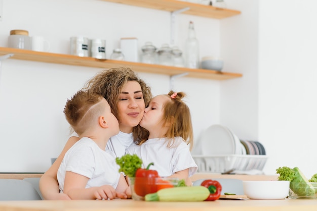 キッチンの家族。子供を持つ美しい母親。白いブラウスの女性。