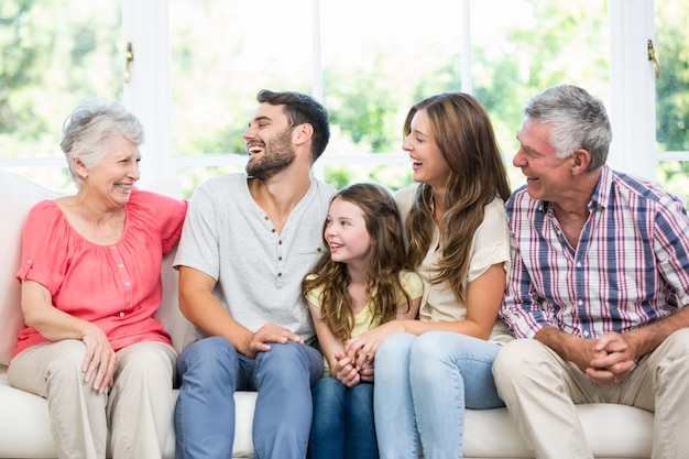 Famiglia che ride mentre sedendosi sul sofà