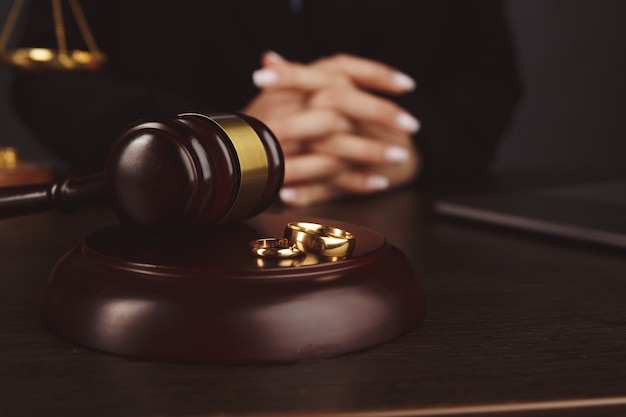 Family law concept, judge gavel and wedding rings on wooden background.