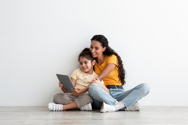 Family Leisure. Happy Arab Mother And Little Daughter Using Digital Tablet Together