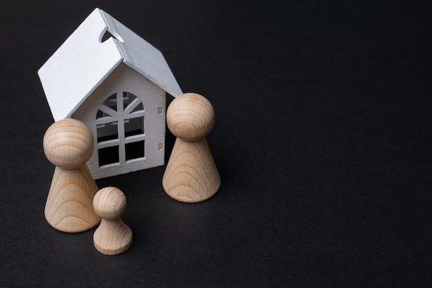 Family life and property insurance concept Wooden figurines representing family and wooden house