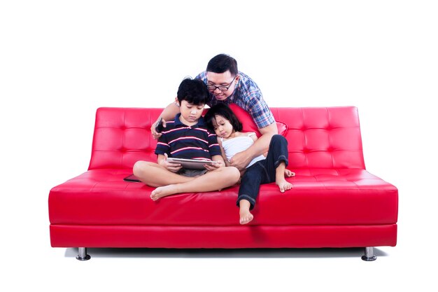 Photo family looking at digital tablet while sitting on sofa against white background