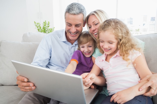Famiglia che esamina computer portatile mentre sedendosi sul sofà