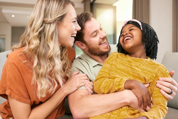 Family love and hug laughing and happiness with care and funny bonding and couple with black child together at family home Happy family adoption or foster care and interracial with relationship
