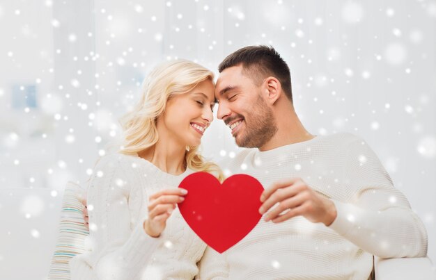 family, love, valentines day and people concept - happy couple with red heart hugging on sofa at home