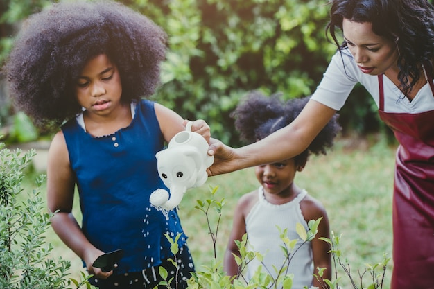 Family lovely gardening watering green plant activity with children during Stay at Home to reduce the outbreak of the Coronavirus. children watering the plant at backyard.