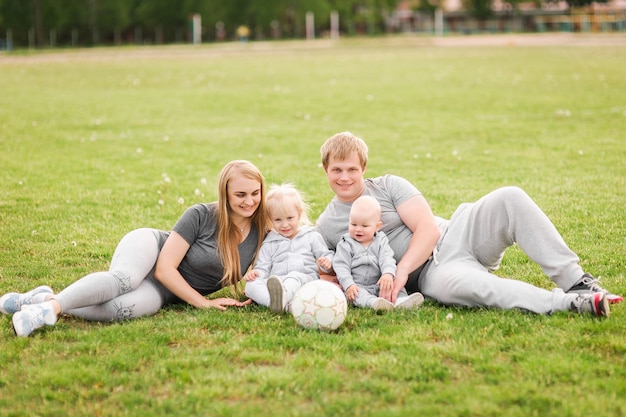 Photo family lying on grass in park together. summer walk, family in nature. mom, dad, i am a sports family. family plays soccer with a ball.