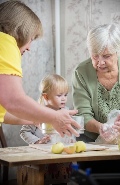 A family making little apple pies two old women and a little girl