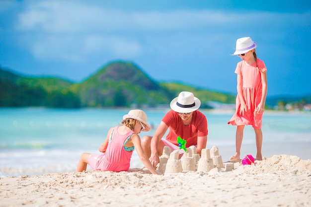 Family making sand castle at tropical white beach