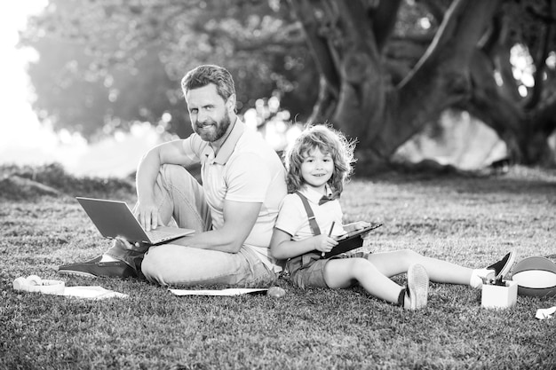 가족 남자 비즈니스 온라인 아버지와 아들이 공원에서 원격으로 노트북 작업을 하고 있습니다.