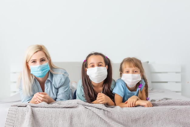 Family in medical face masks lying on a bed quarantine during a COVID-19 coronavirus epidemic