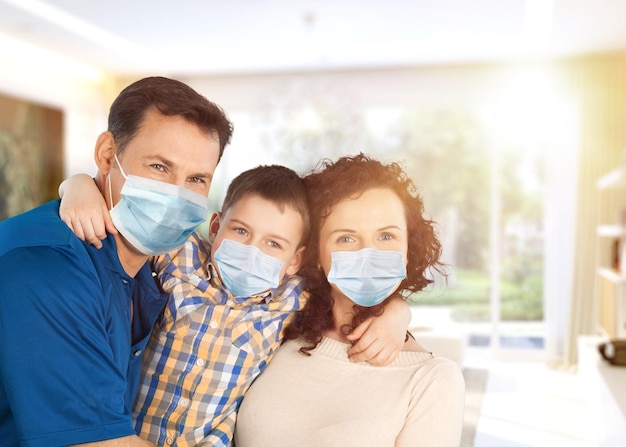 Photo family in medical masks on the face looks at the camera while standing in the room at home.