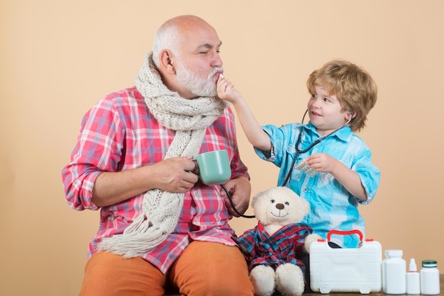 Family medicine concept Parenting Smiling grandfather and his grandson playing with a stethoscope Healthcare profession people and medicine concept