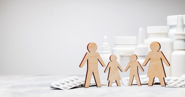 family medicine. dad, mom, daughter and son hold hands on the background of medicines.
