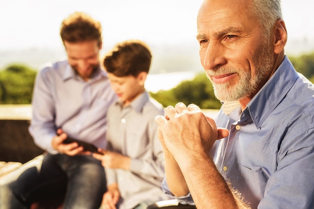 Family Meeting in Park. Old Man Folded Hands.