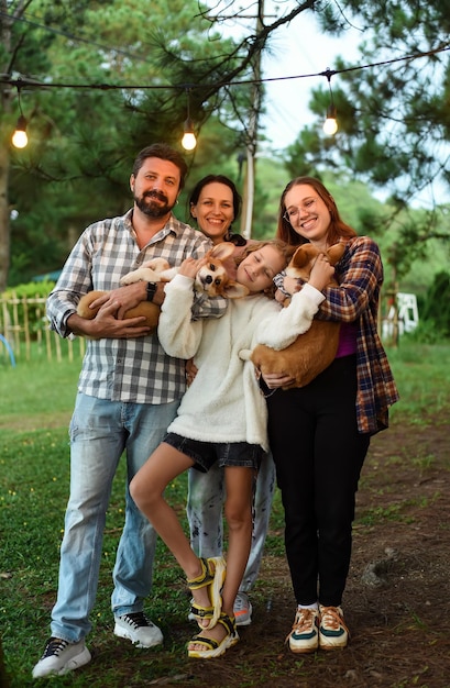 Family members father mother and two daughters with corgi dogs in the forest