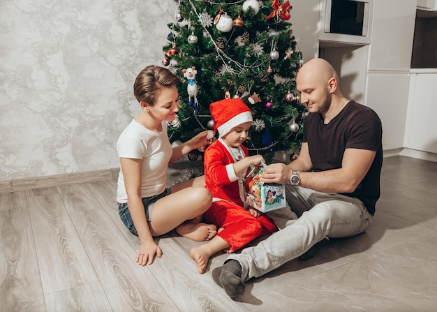 サンタの衣装を着た家族のお母さんお父さんと息子がクリスマスプレゼントを開けます