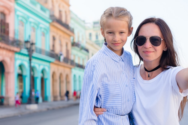 Family of mom and little girl taking selfie in popular area in Old Havana, Cuba. Little kid and young mofther outdoors on a street of Havana