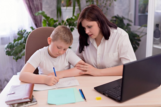 Family mom and son are doing homework in a room on a laptop. Distance learning