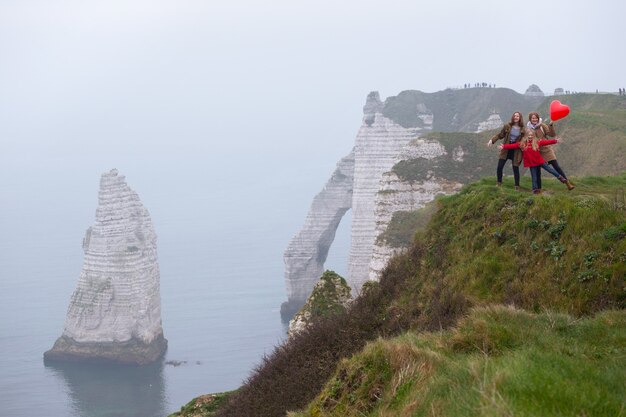 Family. mom and two daughters standing at the edge of rock in the Etretat. France