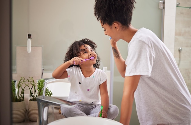 Photo family morning dental cleaning and mother teaching child to brush teeth in bathroom care for mouth health and smile for healthcare with toothbrush girl happy learning about dentistry with mom