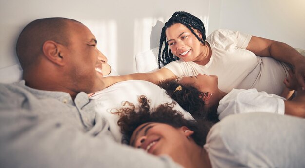 Семейное утро и счастливое утро в домашней спальне, играя в связь и благодарность за любовь Африканская женщина, мужчина и дети лежат вместе для поддержки безопасности или отдыха с матерью и отцом в отпуске