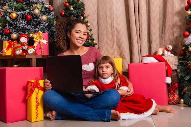 Family mother and child girl use laptop at home on Christmas vacation.