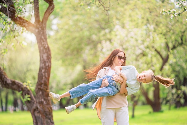 Famiglia della madre e della figlia nel giardino di fioritura della ciliegia