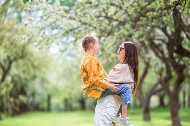 Family of mother and daughter in blooming cherry garden