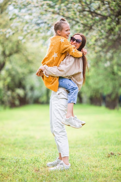 Family of mother and daughter in blooming cherry garden