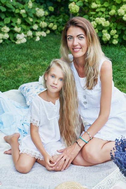 family mother and daughter in the garden in the summer on a picnic rest