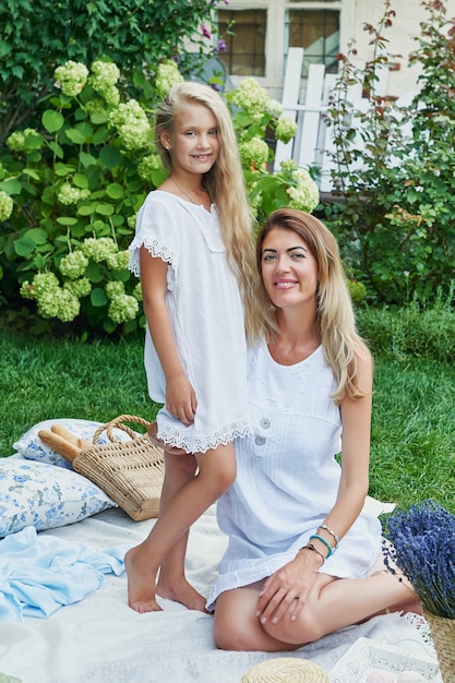 family mother and daughter in the garden in the summer on a picnic rest