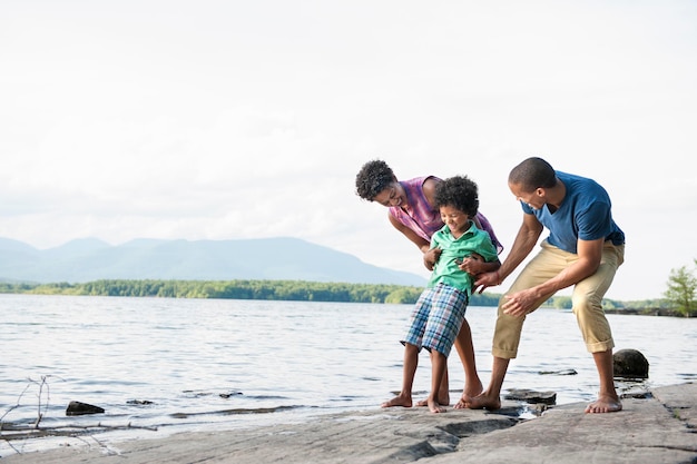 A family mother father and son playing on the shores of a lake