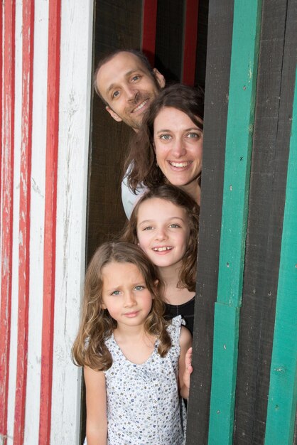 Family mother father and two daughters play outside between two\
wooden huts